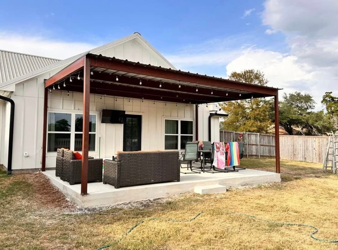 Modern patio with pergola, outdoor furniture, and decorative lights in a residential backyard.